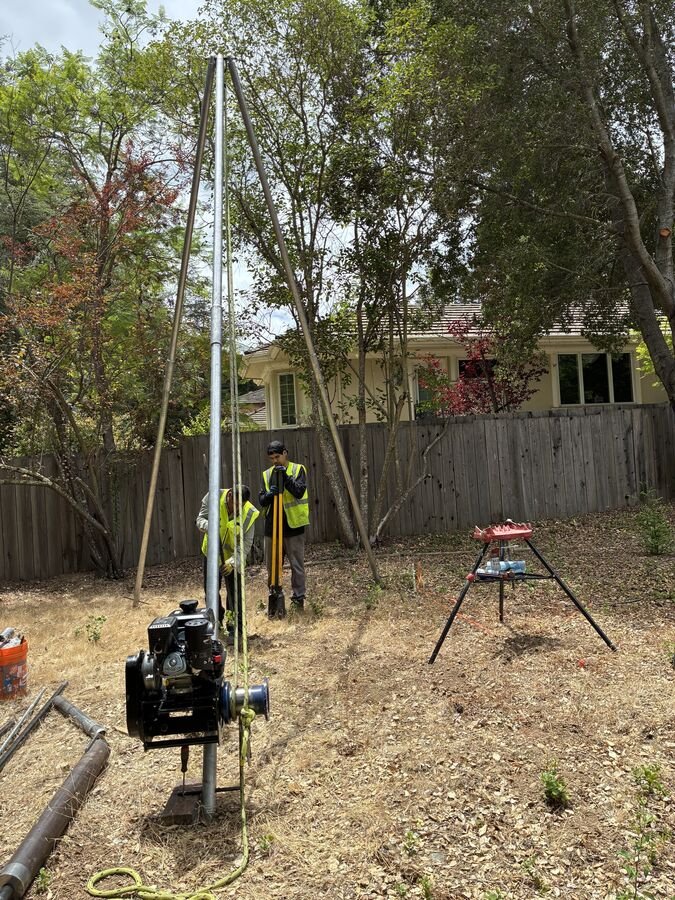 Crew operating a tripod drill rig in a Saratoga backyard for an ADU soil investigation